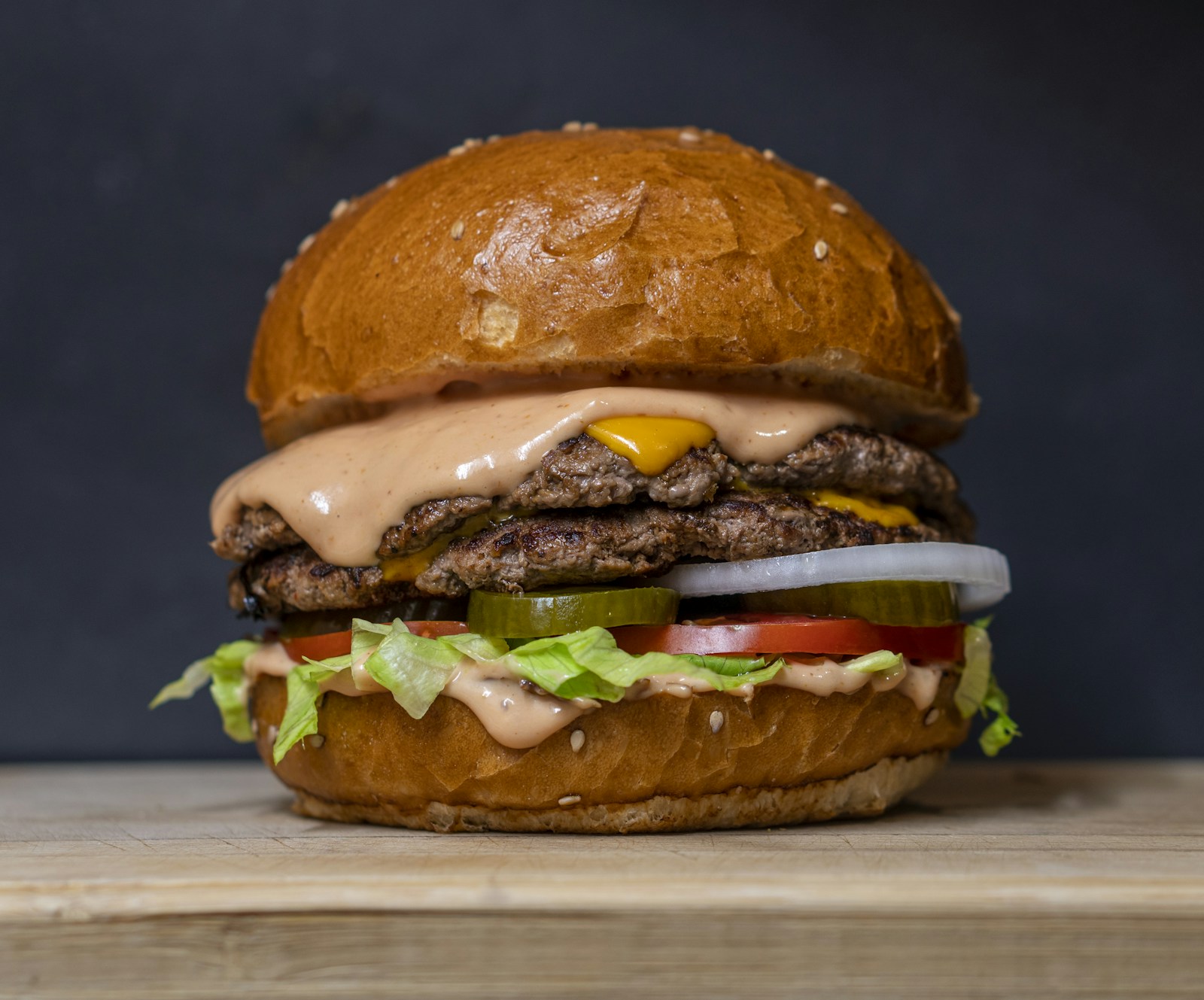 Burger do Burgers N' Smoke com carne alta, queijo e fritas em fundo escuro